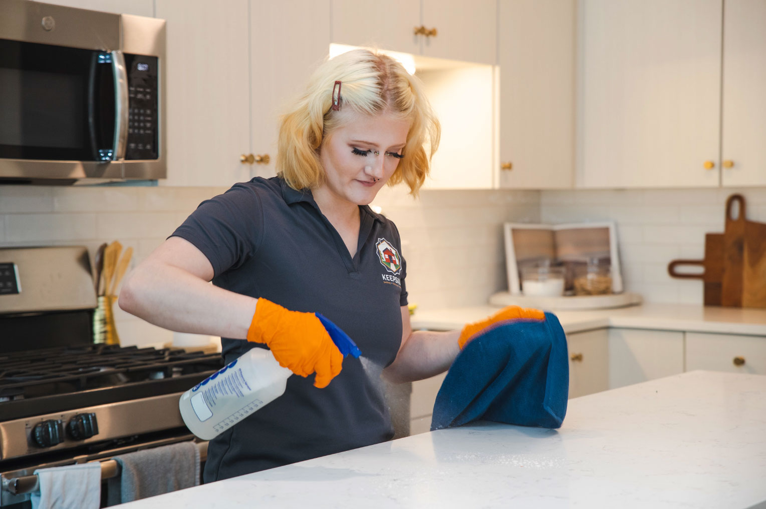 A Keepsake employee spraying cleaning solution onto a kitchen counter