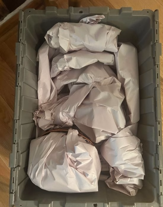 Fragile items wrapped in packing paper inside of a moving box